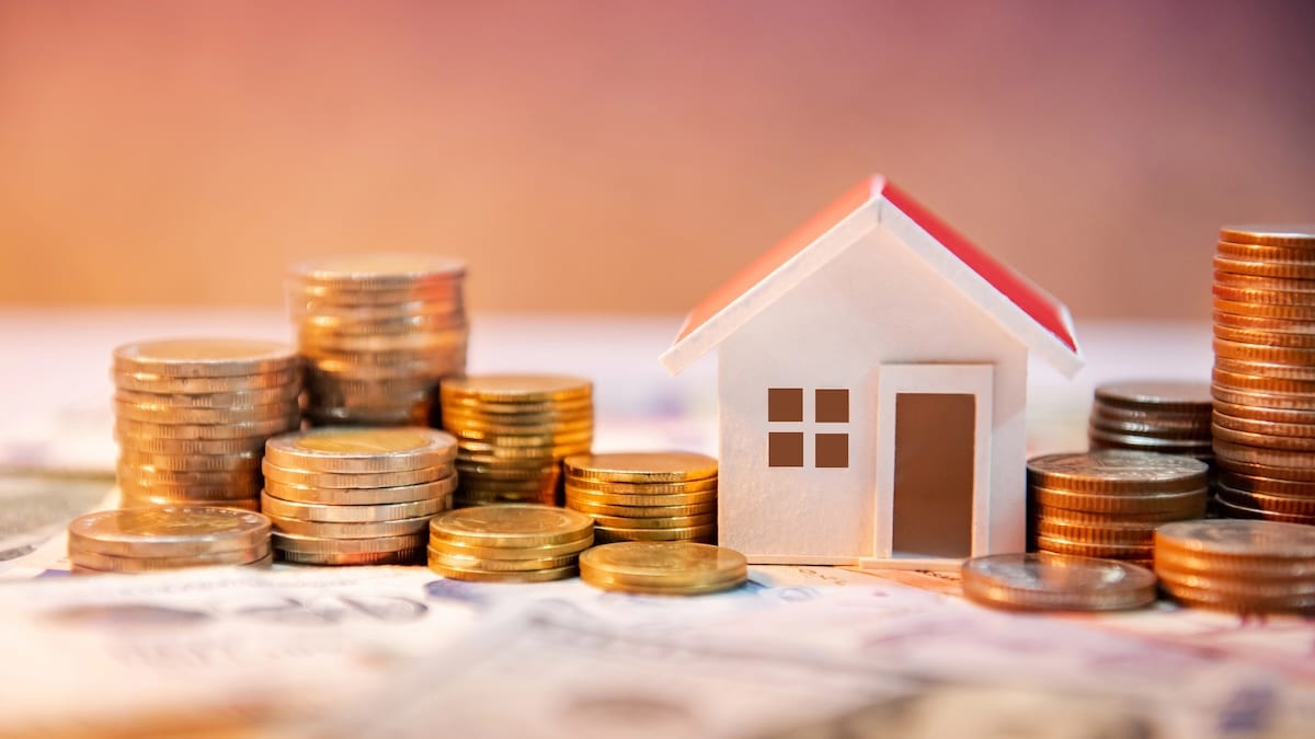 Calcul rendement locatif investissement immobilier - maison miniature entourée de piles de pièces d'or sur documents financiers