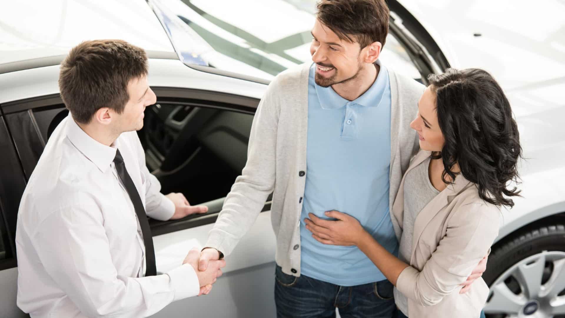 Couple achetant une voiture neuve chez un concessionnaire discutant de l'assurance auto