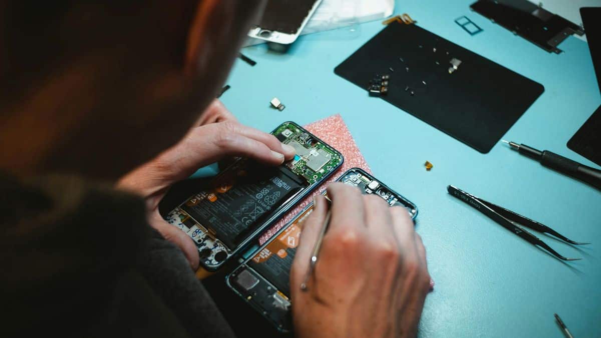 Réparation d'un smartphone ouvert montrant la batterie et les circuits internes
