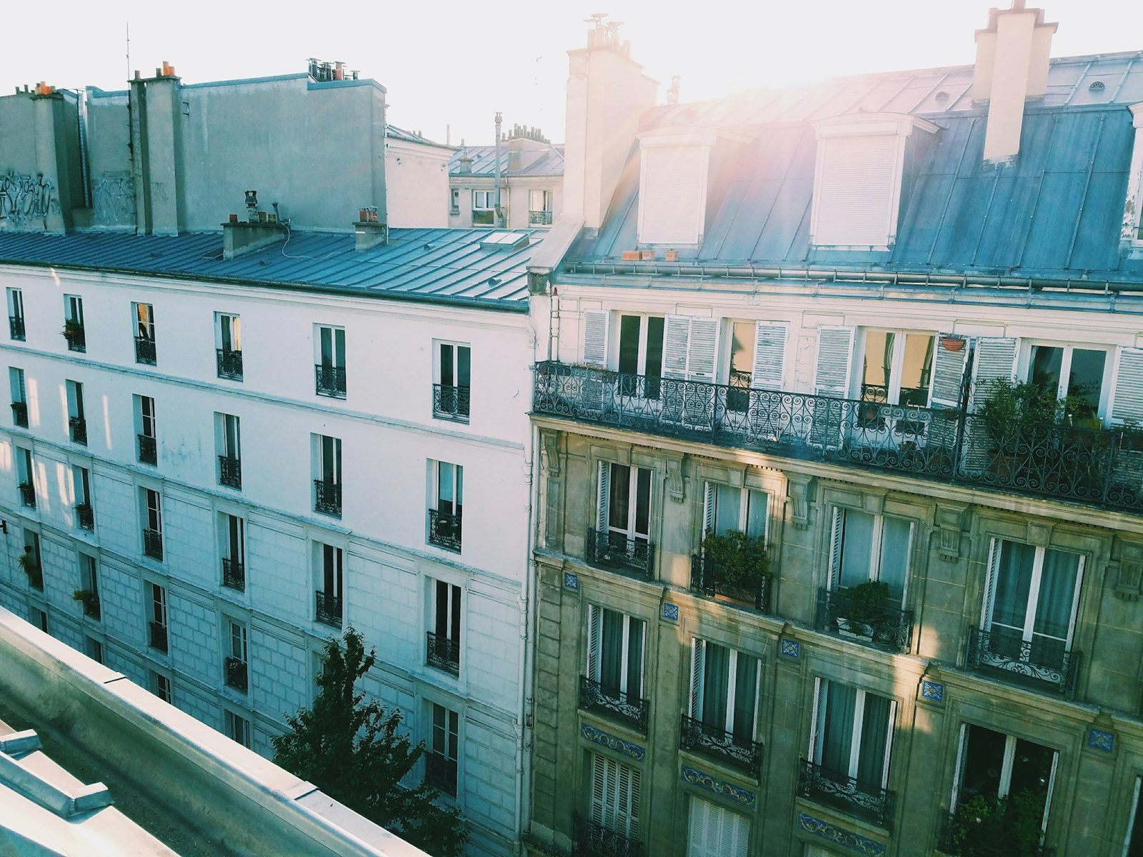 Façades d'immeubles parisiens à balcons filants vues depuis un toit, dans la lumière du matin
