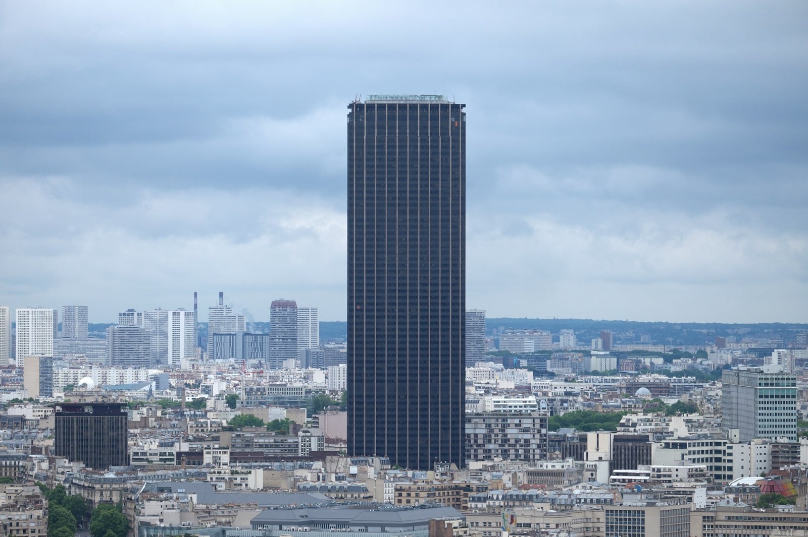La tour Montparnasse, sombre et isolée, domine les toits de Paris sous un ciel gris