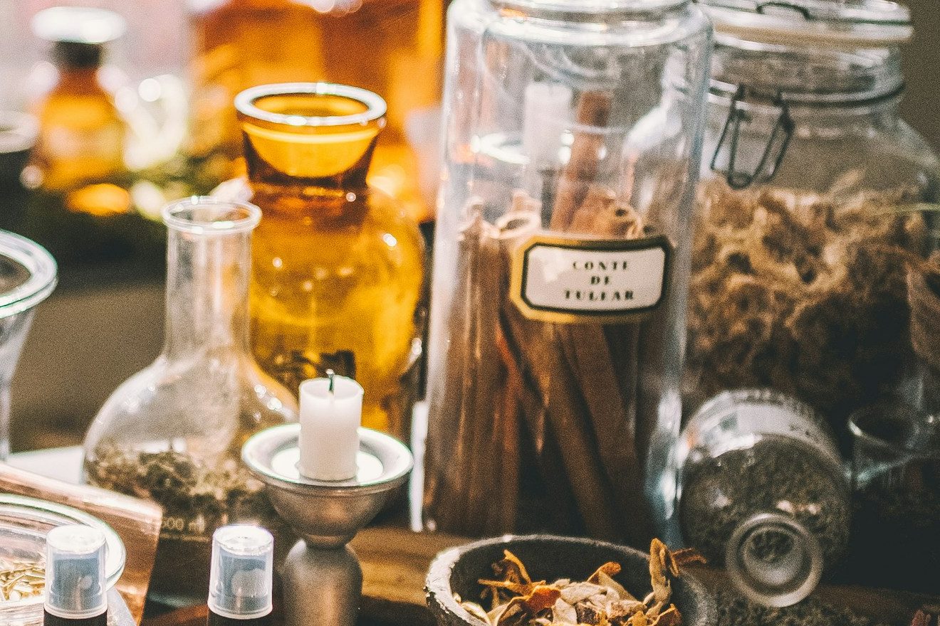 Bocaux de plantes séchées, bâtons de cannelle et flacons ambrés sur une table d'herboristerie